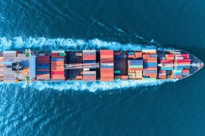 Karbon emisyonlarını azaltmayı hedefleyen dijital sistemlerle donatılmış modern bir konteyner gemisinin denizde ilerleyişini gösteren görsel.