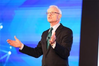 Harvard Business School profesörü Michael E. Porter’ın takım elbiseli, ciddi bakışlarla poz verdiği portresi.