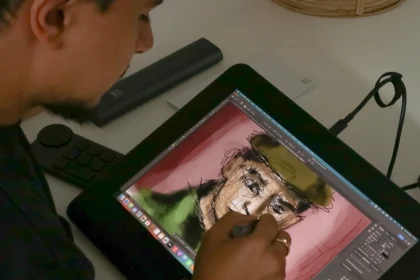 Grafik tablet üzerinde bir portre çizen sanatçının yakın çekim fotoğrafı; dijital sanat üretimi süreci.